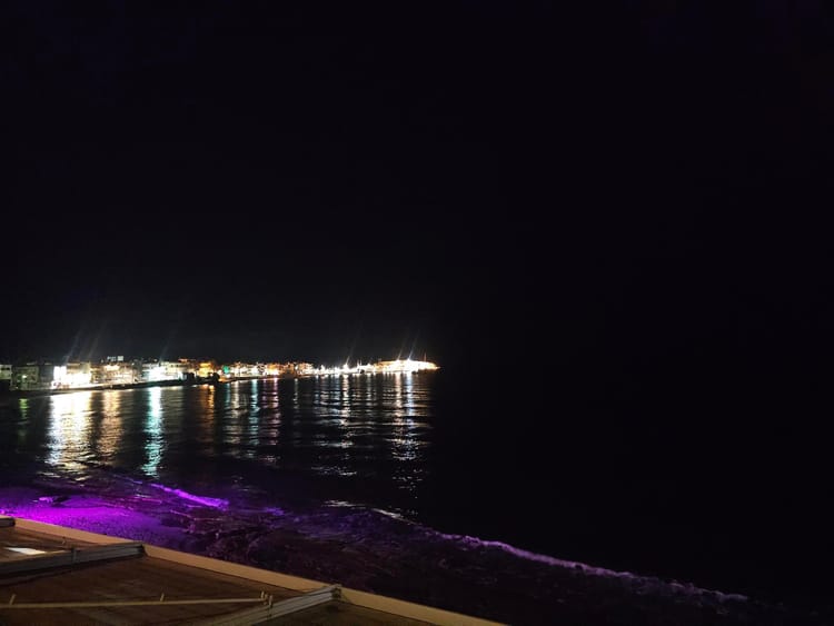 A picture of the beach at night, with the lights of the houses and clubs
