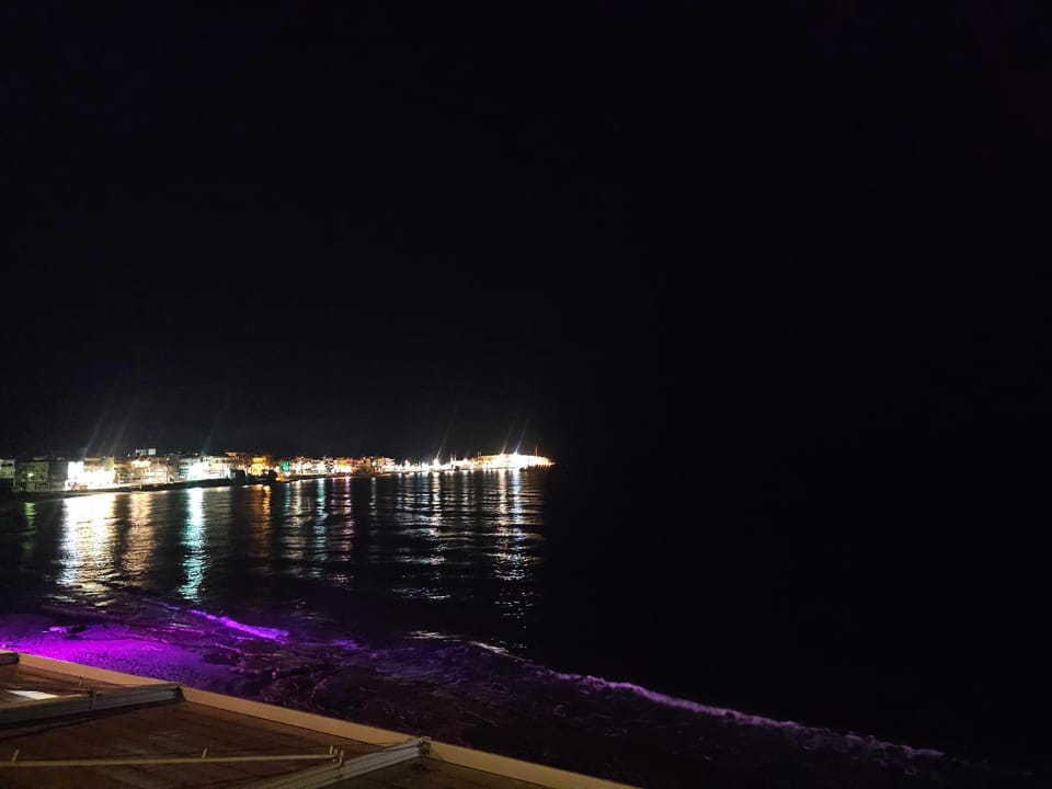A picture of the beach at night, with the lights of the houses and clubs